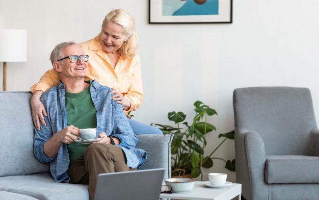 Happy senior couple in living room illustrates blog "What Is Medicare Advantage Annual Enrollment Period?"