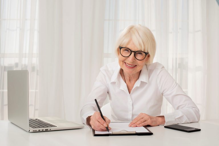 Senior lady sitting at desk illustrates blog "Is Medicare Advantage the same as Medicare?"