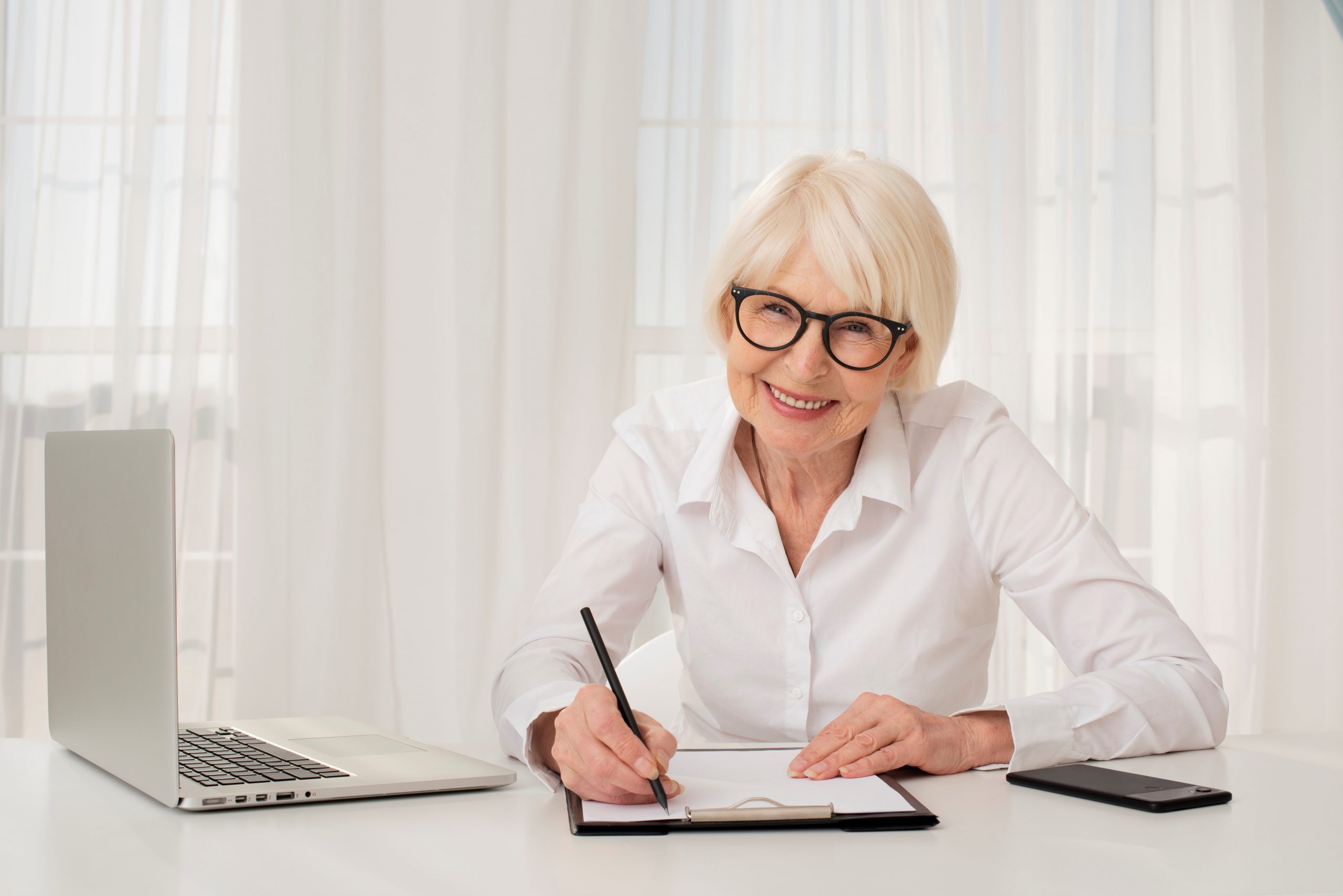 Senior lady sitting at desk illustrates blog "Is Medicare Advantage the same as Medicare?"