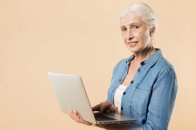 Senior lady holding laptop illustrates blog "Does Medicare Advantage Cover Root Canals?"